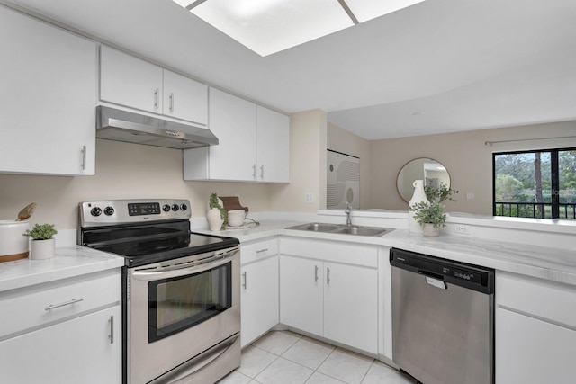 kitchen with sink, light stone countertops, white cabinetry, light tile patterned floors, and appliances with stainless steel finishes