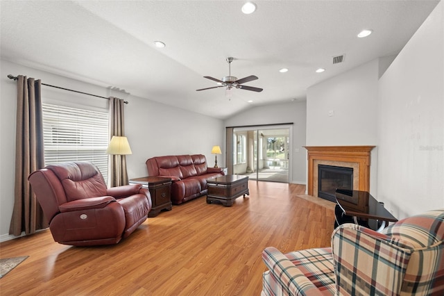 living room featuring light hardwood / wood-style floors, ceiling fan, a textured ceiling, and vaulted ceiling