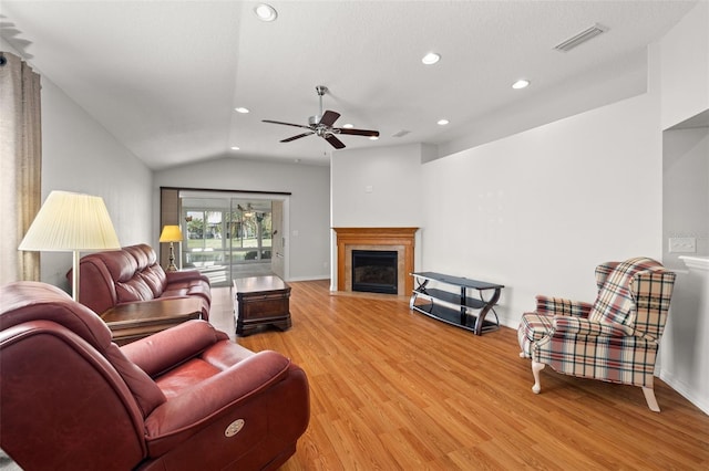 living room with a textured ceiling, light hardwood / wood-style floors, lofted ceiling, and ceiling fan