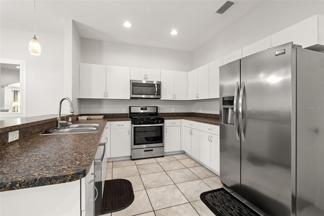 kitchen with light tile patterned flooring, stainless steel appliances, white cabinetry, hanging light fixtures, and sink