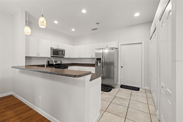 kitchen featuring pendant lighting, white cabinetry, appliances with stainless steel finishes, and kitchen peninsula