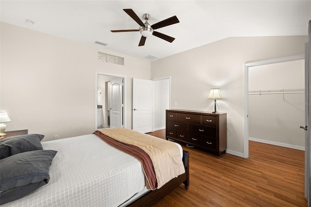 bedroom featuring ceiling fan, wood-type flooring, a walk in closet, lofted ceiling, and a closet