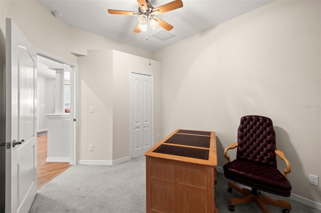 carpeted office space featuring ceiling fan and decorative columns