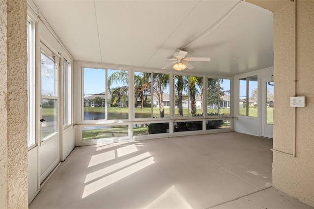 unfurnished sunroom with ceiling fan and a water view