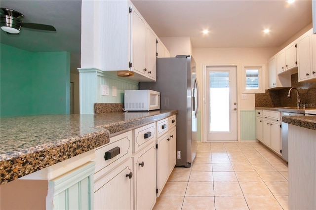 kitchen featuring decorative backsplash, white cabinetry, dark stone countertops, and sink