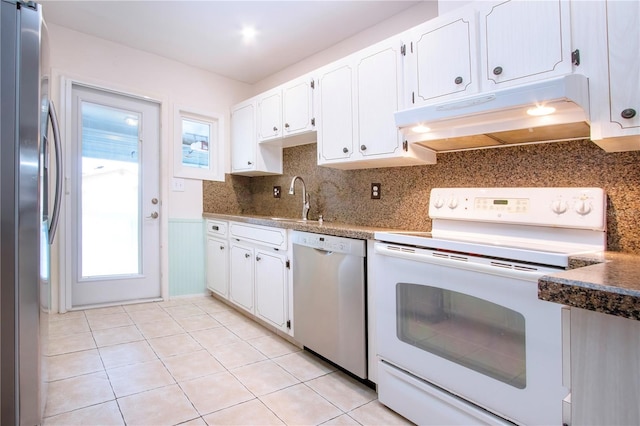 kitchen featuring tasteful backsplash, appliances with stainless steel finishes, sink, white cabinets, and light tile patterned floors