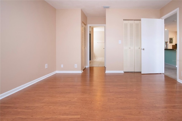 unfurnished bedroom with light hardwood / wood-style floors and multiple closets