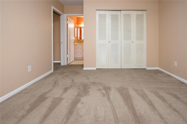 unfurnished bedroom with a closet, connected bathroom, and light colored carpet