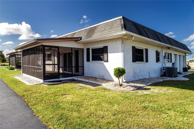 rear view of property featuring a yard, a sunroom, and central AC unit