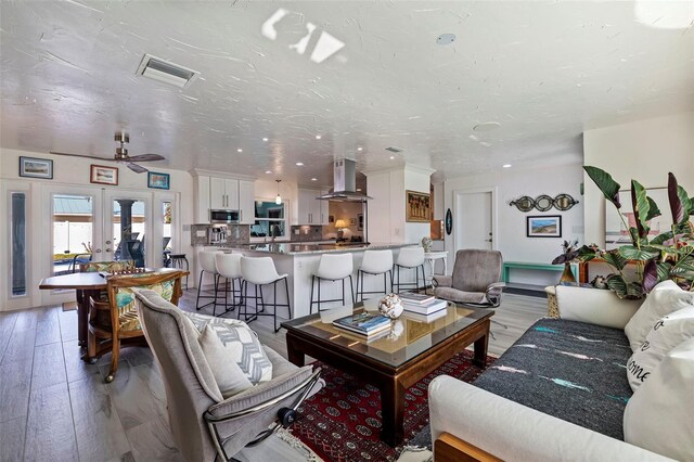 living room featuring a textured ceiling, ceiling fan, hardwood / wood-style floors, and french doors