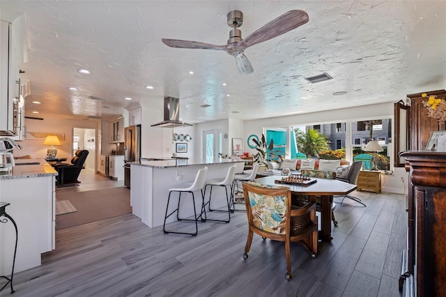 dining area with wood-type flooring, a textured ceiling, and ceiling fan