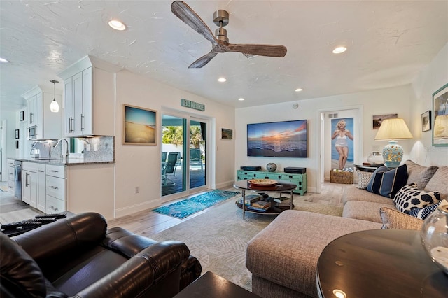 living room featuring light hardwood / wood-style flooring, ceiling fan, and sink