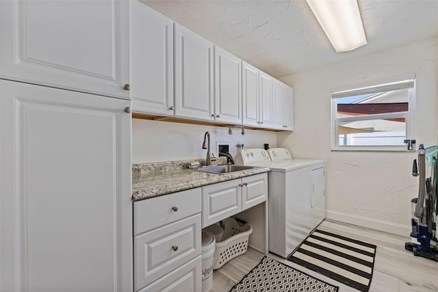 washroom with cabinets, washing machine and dryer, light hardwood / wood-style floors, and sink