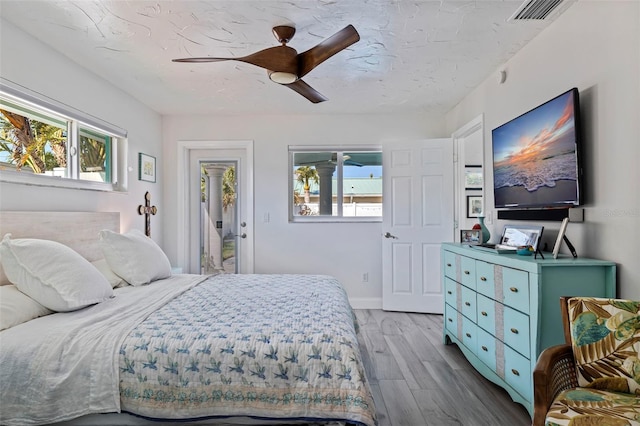 bedroom featuring ceiling fan, light hardwood / wood-style floors, and multiple windows