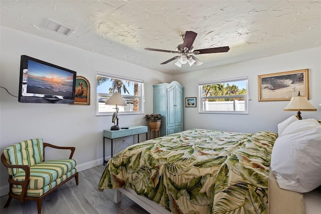 bedroom featuring multiple windows, hardwood / wood-style floors, and ceiling fan