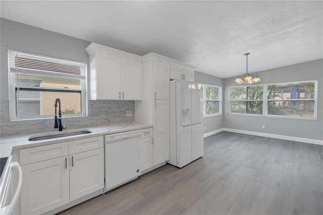 kitchen with tasteful backsplash, white cabinetry, sink, and white appliances