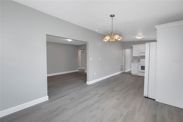 kitchen with white appliances, white cabinets, light hardwood / wood-style flooring, tasteful backsplash, and a chandelier