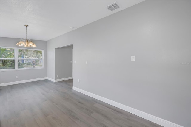 spare room featuring hardwood / wood-style floors and an inviting chandelier