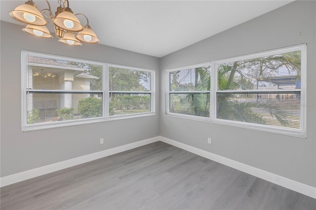 unfurnished room featuring plenty of natural light, hardwood / wood-style floors, and vaulted ceiling