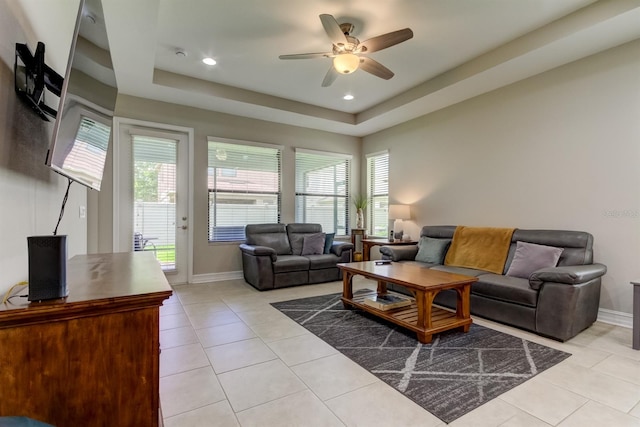 tiled living room featuring ceiling fan, a healthy amount of sunlight, and a tray ceiling