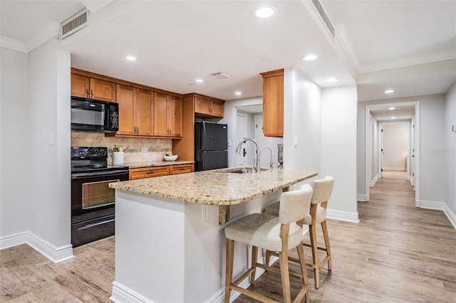 kitchen with sink, black appliances, light stone countertops, crown molding, and light wood-type flooring