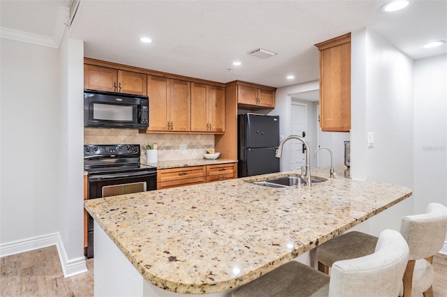 kitchen featuring tasteful backsplash, light hardwood / wood-style flooring, black appliances, crown molding, and sink