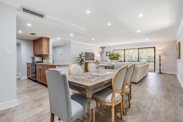 dining area with sink, crown molding, and light hardwood / wood-style floors