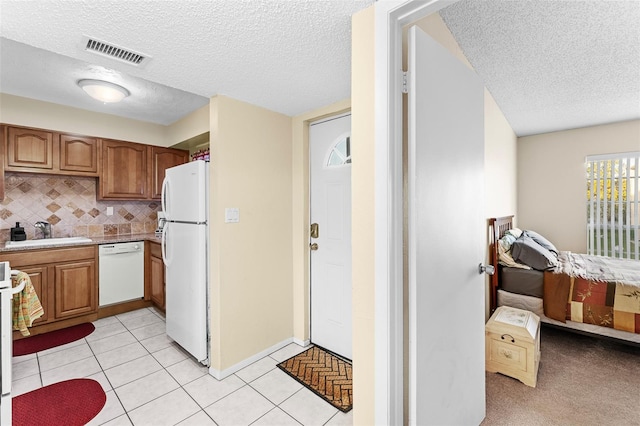 kitchen featuring a textured ceiling, sink, light tile patterned floors, and white appliances