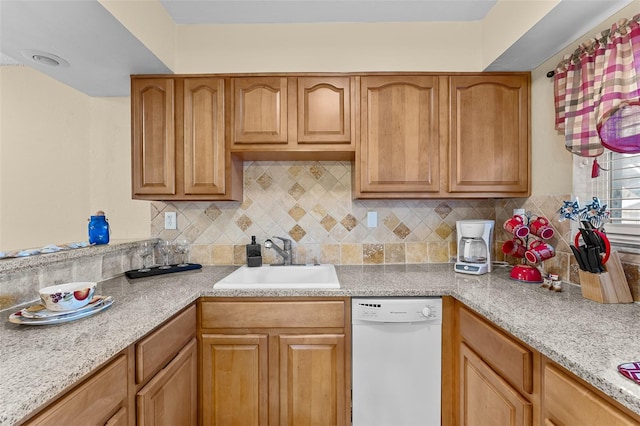 kitchen featuring light stone countertops, backsplash, white dishwasher, and sink