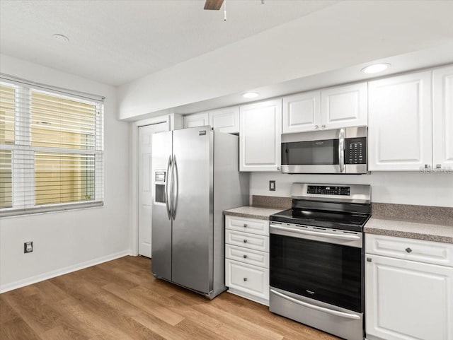 kitchen with white cabinets, stainless steel appliances, light hardwood / wood-style floors, and ceiling fan