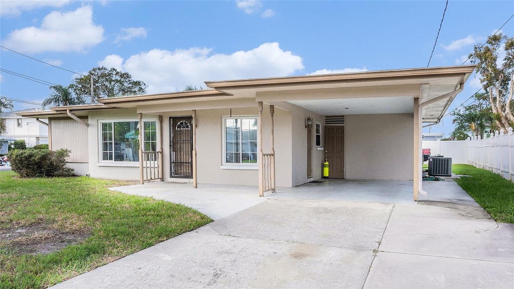 view of front of home with a carport, cooling unit, and a front yard