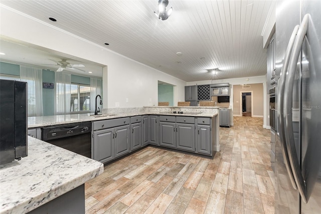 kitchen featuring sink, black appliances, light stone countertops, light wood-type flooring, and gray cabinets