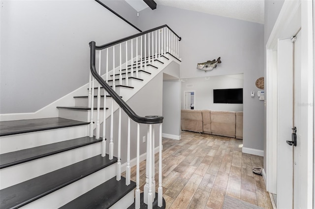 stairs with a textured ceiling, vaulted ceiling, and hardwood / wood-style floors