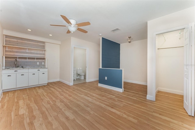 unfurnished living room featuring sink, light wood-type flooring, and ceiling fan