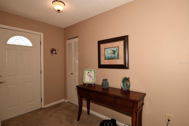 carpeted foyer featuring a textured ceiling