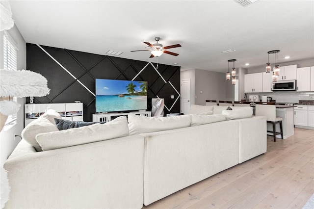 living room with light hardwood / wood-style floors and ceiling fan