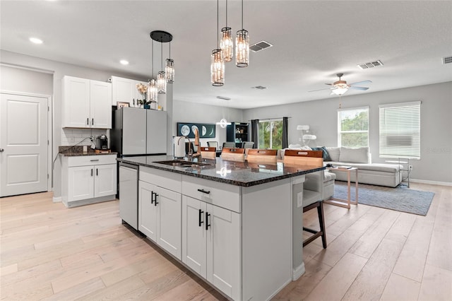 kitchen featuring a center island with sink, sink, and white cabinets