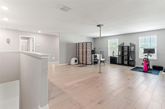 exercise room with light hardwood / wood-style flooring and a textured ceiling