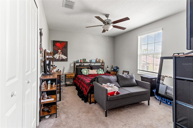 carpeted bedroom with a textured ceiling, a closet, and ceiling fan