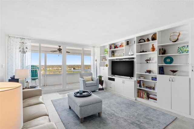 living room with ceiling fan and a textured ceiling