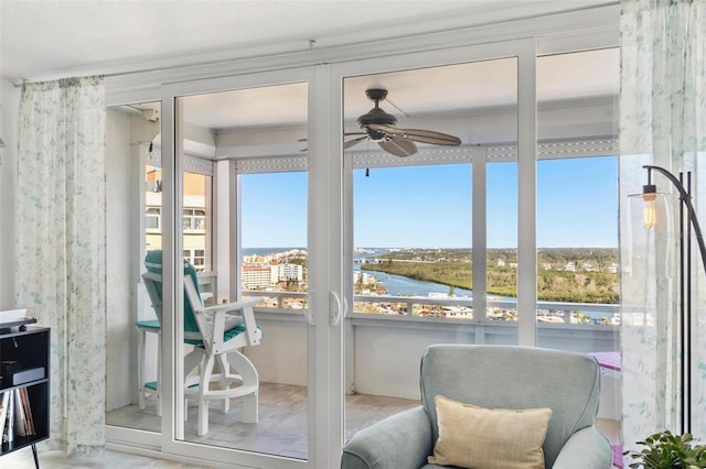 sunroom featuring ceiling fan and a water view