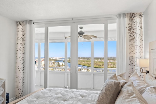 bedroom featuring ceiling fan, a water view, and a textured ceiling