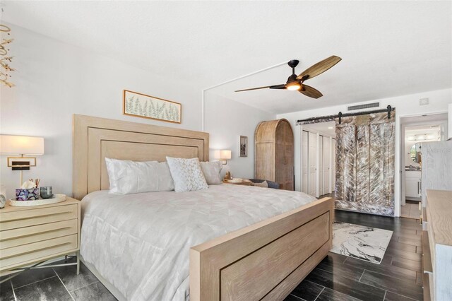 bedroom featuring ceiling fan, a barn door, and ensuite bath