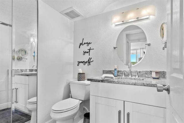 bathroom featuring a textured ceiling, toilet, and vanity