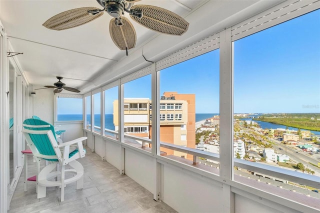 sunroom with ceiling fan, a water view, and a healthy amount of sunlight