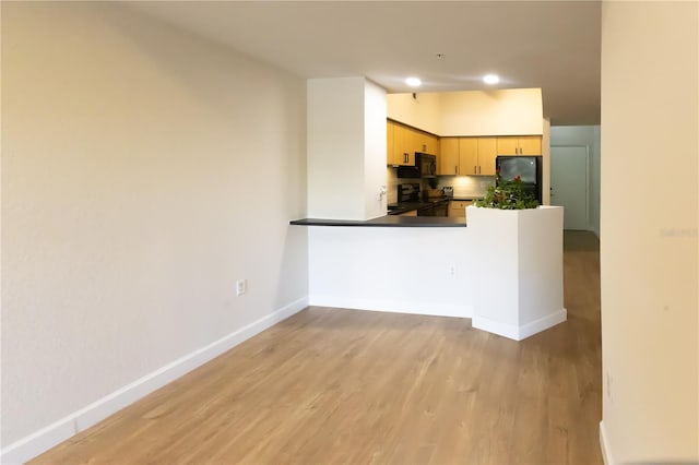 kitchen with black appliances, light brown cabinetry, tasteful backsplash, light hardwood / wood-style floors, and kitchen peninsula