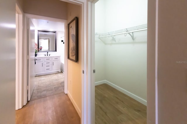 corridor with light hardwood / wood-style flooring and sink