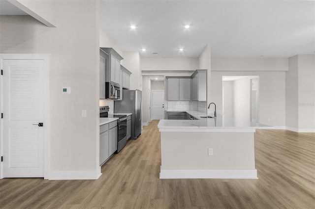 kitchen featuring stainless steel appliances, tasteful backsplash, gray cabinets, and light wood-type flooring