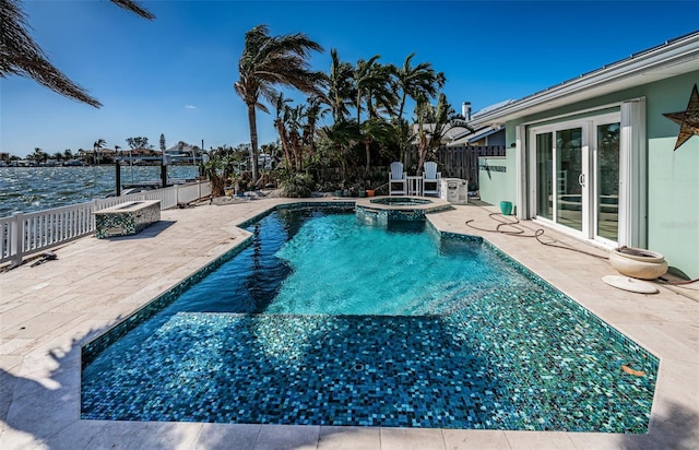 view of swimming pool featuring a patio, a water view, and an in ground hot tub