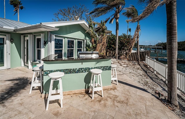 view of patio / terrace with a water view, area for grilling, and an outdoor bar